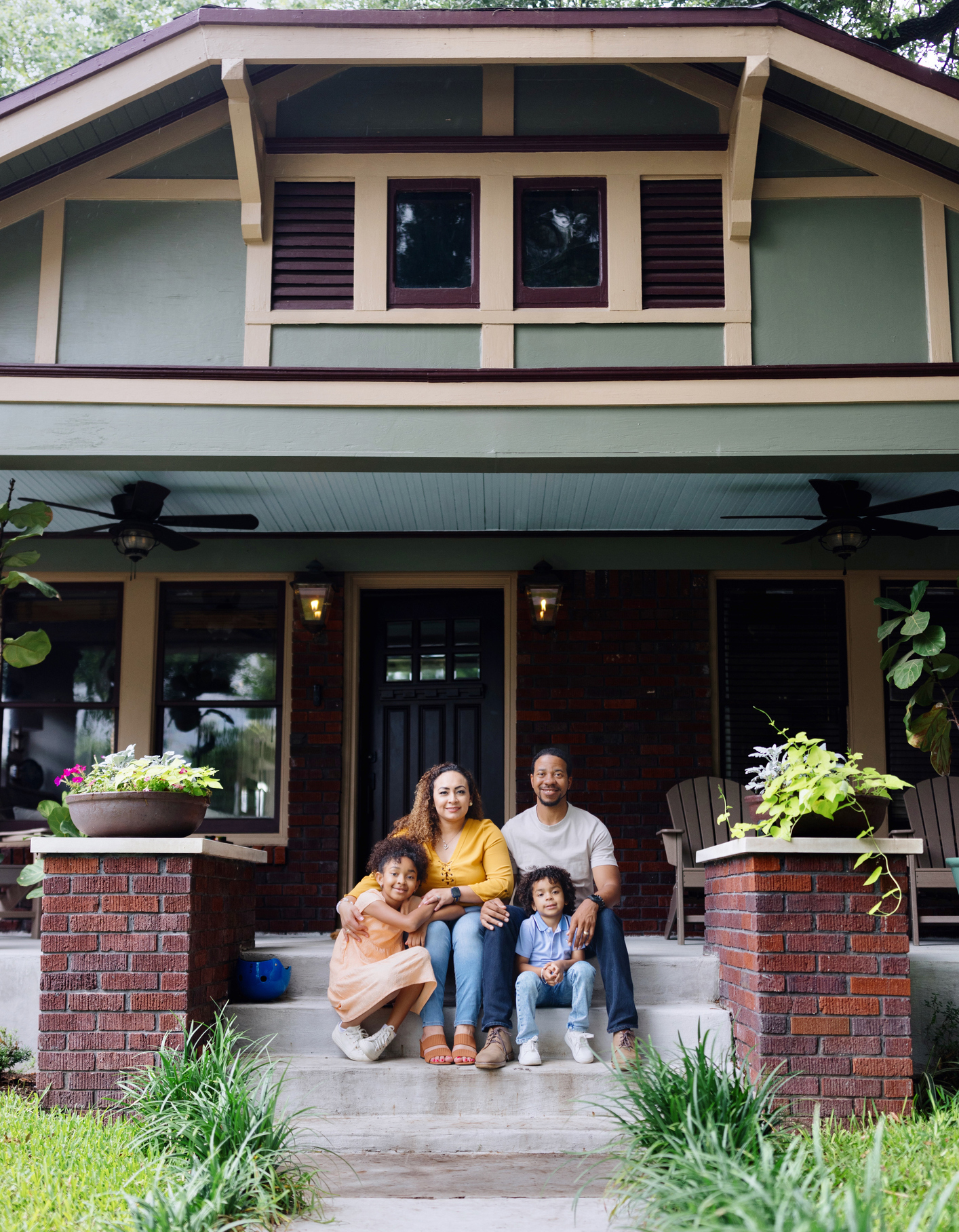 Portrait of a family with two children sitting in front of the house
